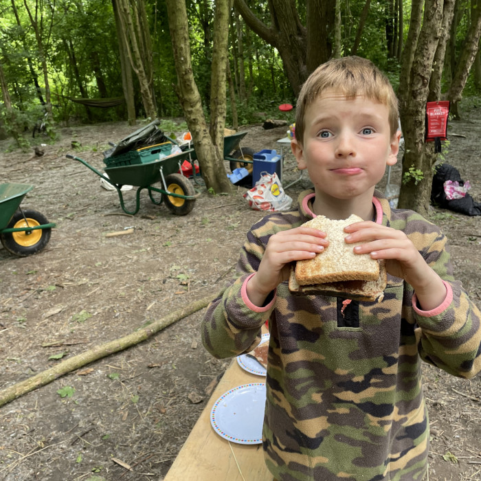A boy is eating a campfire snack with a big grin