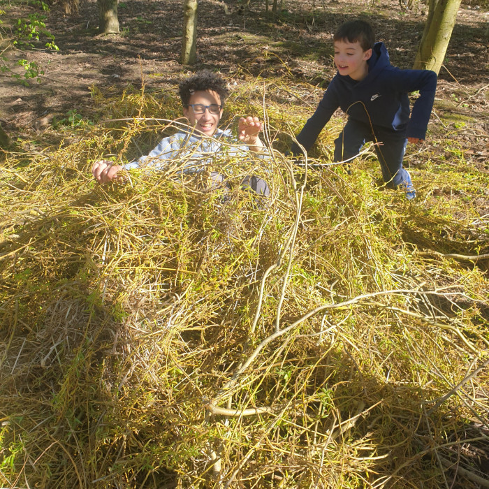 Two young people building a nest out of natural material